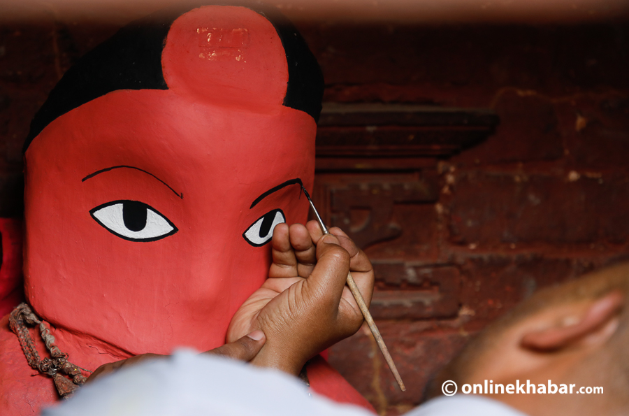 A priest painting eyes on Rato Machhindranath after its annual bathing ritual.