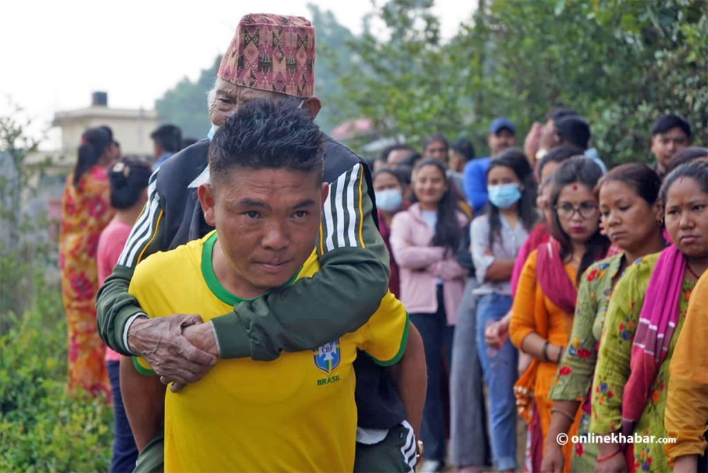 A young man carried an old man to a voting station for the local elections, in Kathmandu, on Friday, May 13, 2022.
