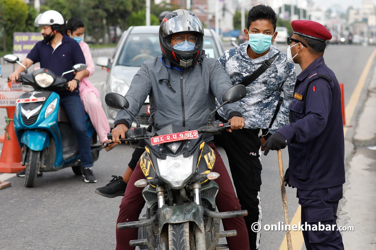 File: A policeman interrogates a biker for flouting the odd-even rationing in Kathmandu.