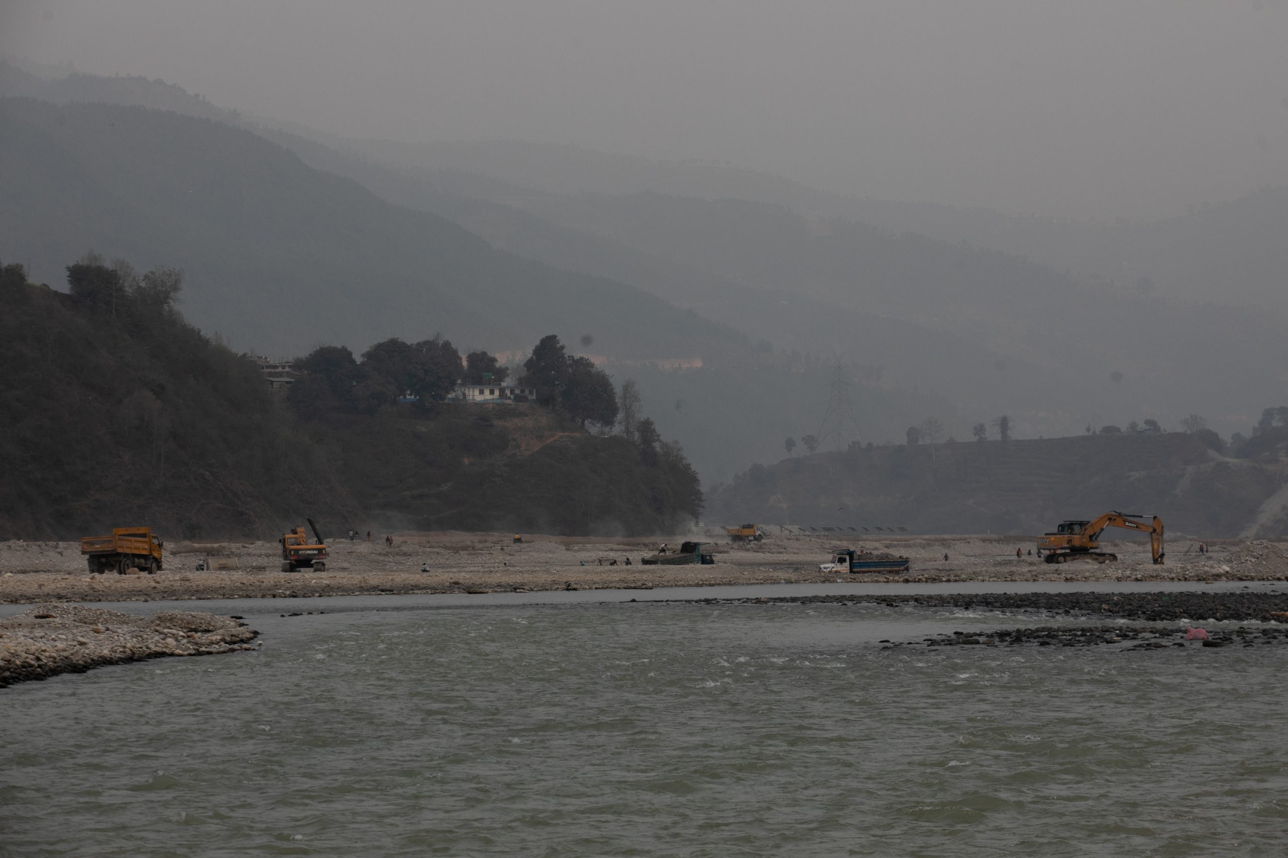 Excavators and trucks lined up along the banks of the Indrawati river in Sindhupalchok. Photo: Bikram Rai for CIJ
