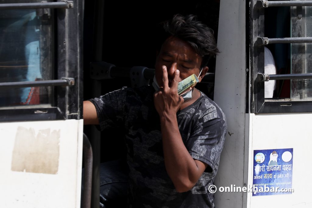 A bus conductor carries notes in his hands