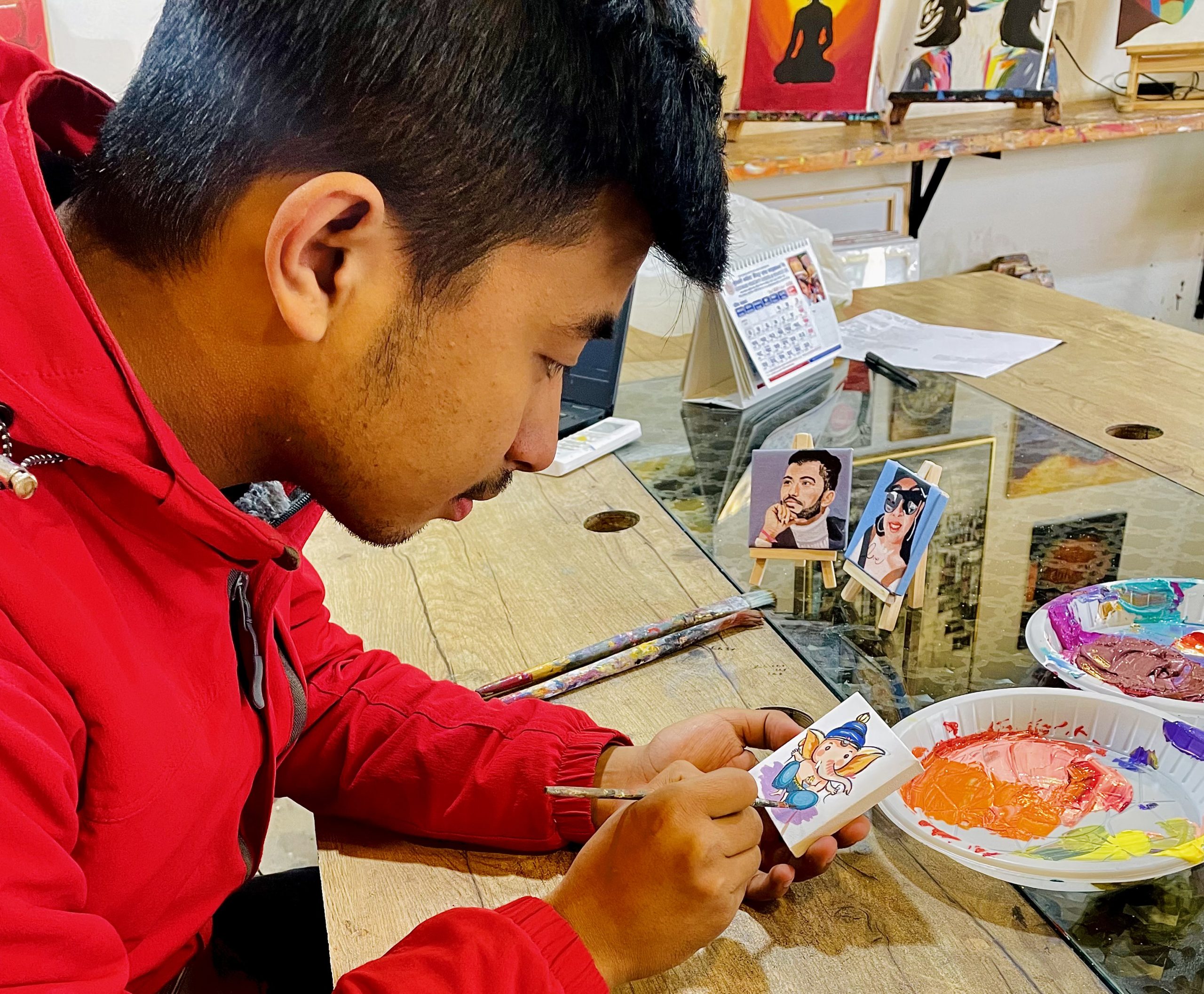 Aman Shakya painting on a mini canvas. Photo: Canvasso Nepal