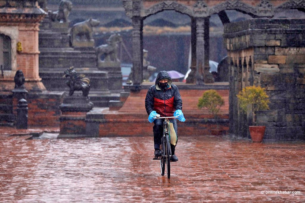 A man on his bicycle pedals past the Bhaktapur Durbar Square during a rain, on Wednesday, December 29, 2021. Photo: Bikash Shrestha winter rainfall
