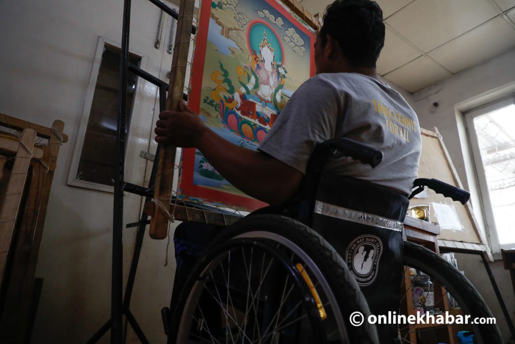 A disabled man prepares a thangka painting using his professional skills.