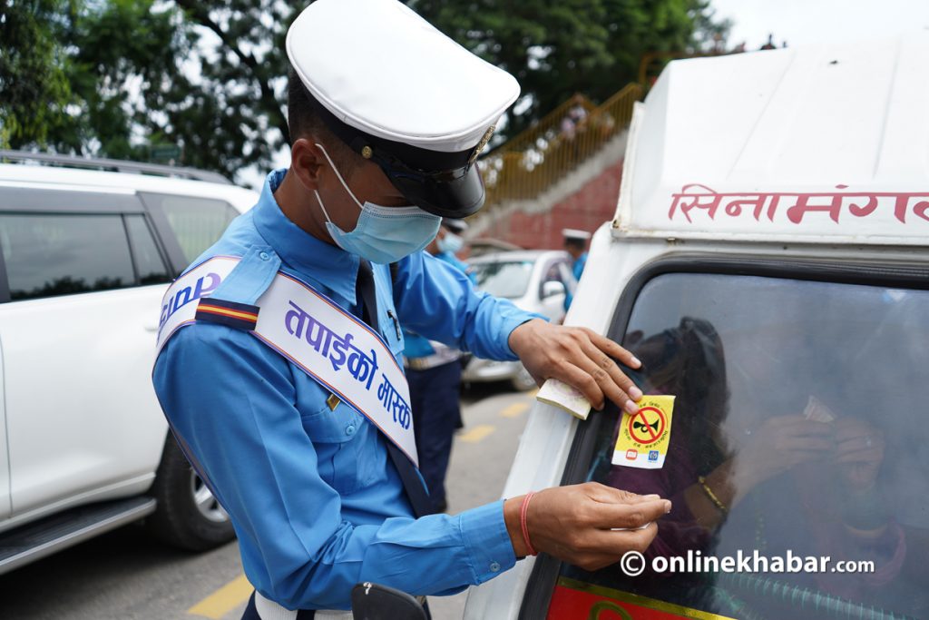 A traffic policeman pastes a sticker to discourage vehicles for implementing the no-horn provision, in Kathmandu, in August 2022.
