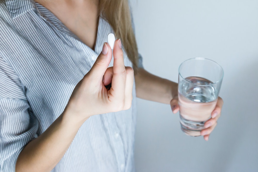 woman taking oral medicine- pill