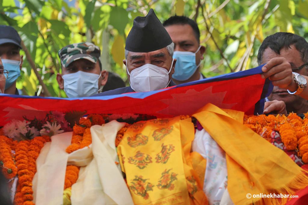 Prime Minister Sher Bahadur Deuba drapes the national flag on Satya Mohan Joshi's body, in Kathmandu, on Sunday, October 16, 2022. Photo: Aryan Dhimal