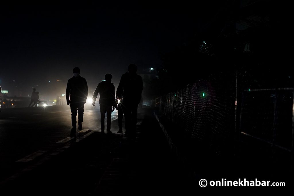 File: Pedestrians walk along a dark pavement as street lights have gone non-operational in Kathmandu. 