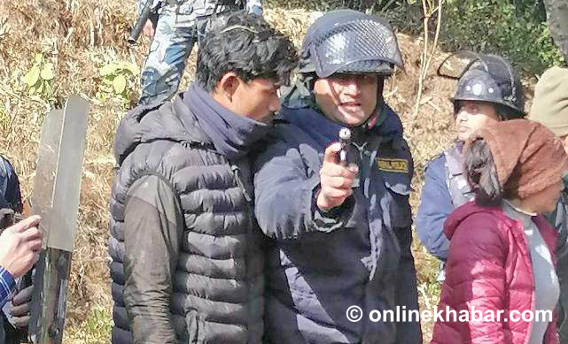 Police Inspector Bishal Bahadur Budhathoki points a pistol at locals at Bojheni, Shankharapur, on Friday, January 6, 2022.