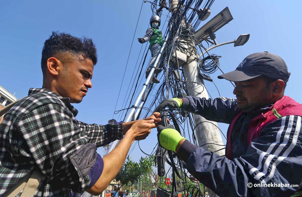 Workers remove unorganised wires from roadside poles in Kathmandu, on Monday, May 8, 2023. Photo: Aryan Dhimal
