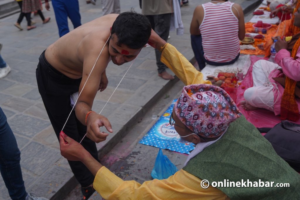 A man wears a janai offered by a priest on the day of Janai Purnima, August 31, 2023. Photo: Chandra Bahadur Ale