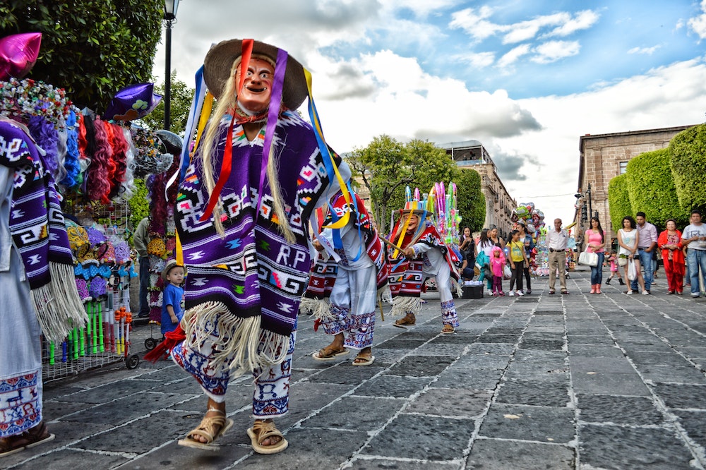 People in traditional attires celebrating on the streets of Mexico. Photo: Pexels/ Genaro Servín